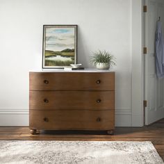 a wooden dresser sitting on top of a hard wood floor next to a white door