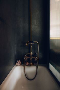 a bathtub in a black bathroom with a gold faucet