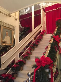 the staircase is decorated with red and green garlands, poinsettias, and greenery