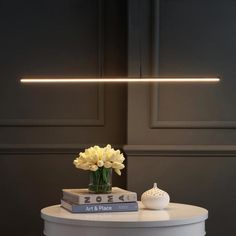 a white table topped with two books and a vase filled with flowers on top of it