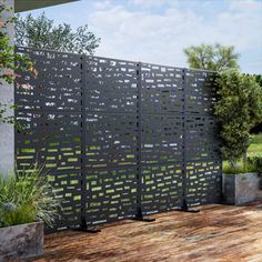 a wooden deck next to a fence with plants and trees in the backgroud