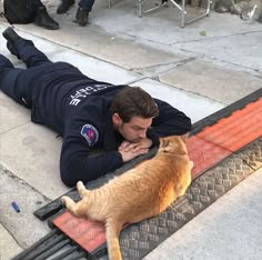 a man laying on the ground next to a cat