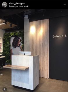 a woman is sitting at a desk in front of a laptop on the table and behind her she is an advertisement for salon 17