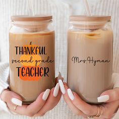 two coffee mugs with the words, thank you and teacher written on them are being held by someone's hands