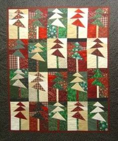 a quilted wall hanging with trees and plaids on the bottom, along with red and green accents