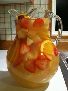 a pitcher filled with fruit sitting on top of a counter next to a stovetop