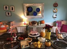 a dining room table is set with plates and fruit on it, candles in the center