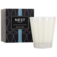 a candle in front of a box with the label nest ocean mist and sea salt