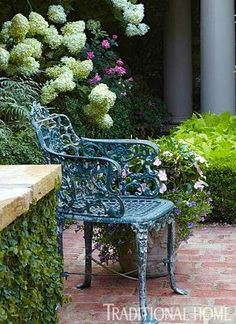 there is a bench in front of some flowers and plants on the side walk way