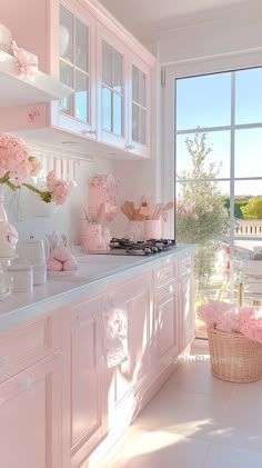 a kitchen with white cabinets and pink flowers in vases on the counter top, next to a large window