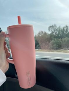 a person holding a pink coffee cup in their car