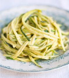 pasta with zucchini and parmesan cheese on a blue and white plate