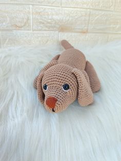 a crocheted dog laying on top of a white fur covered floor