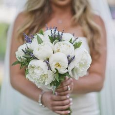 a bride holding a bouquet of white flowers