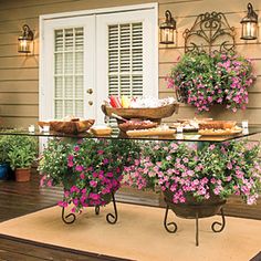 an outdoor dining area with potted plants and flowers on the table, next to a door