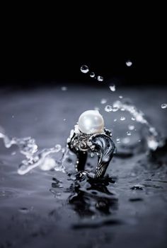 a ring with a pearl in the middle of water