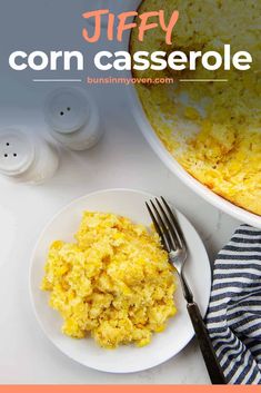 a white plate topped with scrambled eggs next to a bowl of corn casserole