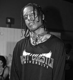 a young man with dreadlocks standing in front of a group of other people