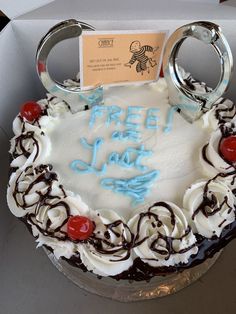 a birthday cake in a box with the words free from love written on it and two handcuffs