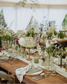 the table is set with flowers, candles and place settings for an outdoor dinner party