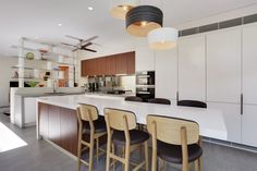 a kitchen with white counter tops and wooden stools