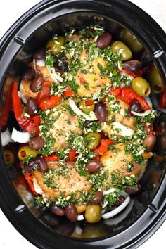 a crock pot filled with chicken, olives and peppers