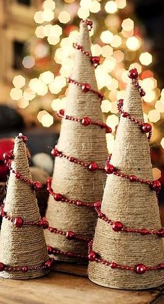 three small christmas trees made out of burlock and beads on a wooden table