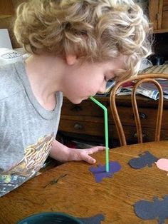 a young boy blowing out a candle on top of a wooden table with mickey mouse cut outs