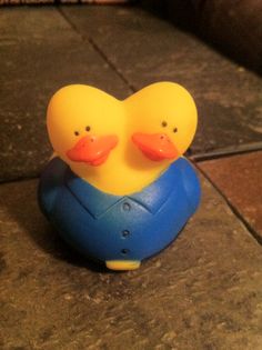 two rubber ducks sitting on top of a tile floor next to a blue object with orange beaks