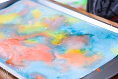 an abstract painting is being made with colored paper and watercolors on a metal tray