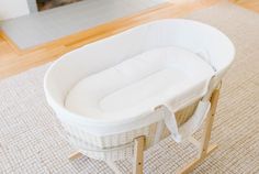 a white wicker baby bassinet sitting on top of a wooden floor next to a fireplace