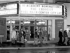 an old movie theater with people walking in front