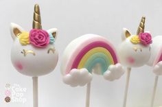 three unicorn lollipops with pink, yellow and blue frosting on them