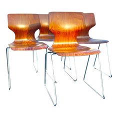 three wooden chairs sitting next to each other on top of a white surface with metal legs