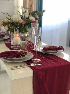 the table is set with silverware and red linens, candles and flowers in vases