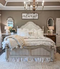 a white bed sitting under a chandelier in a bedroom