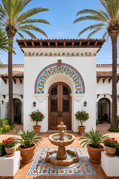 a fountain in the middle of a courtyard with potted plants and palm trees around it