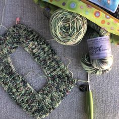 yarn, scissors and knitting needles are laying on the ground next to some fabric material