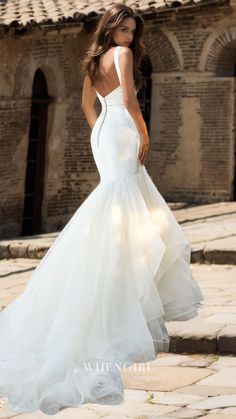 a woman in a white wedding dress standing outside