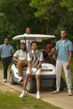 four men are standing in front of a golf cart and one is holding a golf club