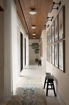 a long hallway with pictures hanging on the wall and a bench in front of it