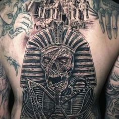 the back of a man with tattoos on his body and an egyptian pyramid behind him