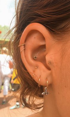 a close up of a person's ear with two piercings on it and people in the background