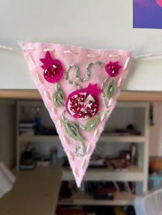 a piece of felt hanging from a clothes line with pomegranates on it