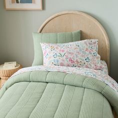 a bed with green bedspread and pink flowers on the comforter in a bedroom