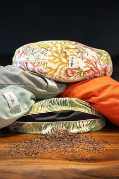 three different colored pillows sitting on top of a wooden table next to some coffee beans