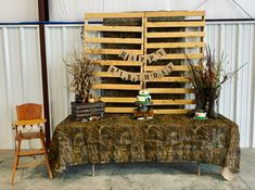 a wooden sign sitting on top of a table next to a chair and potted plant