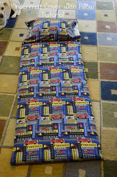 a dog laying on the floor next to a bed with a blue and yellow cover