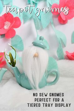 a teapot gnome sitting on top of a white blanket next to pink flowers and text that reads, no sev gnomes perfect for tiered tray display