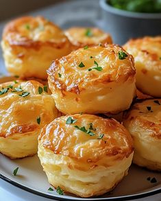 several small pastries on a white plate with green garnishes in the background